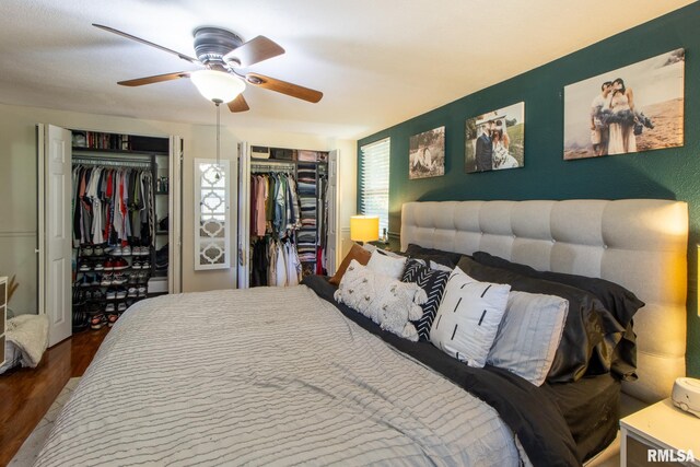 bedroom featuring wood-type flooring, two closets, and ceiling fan