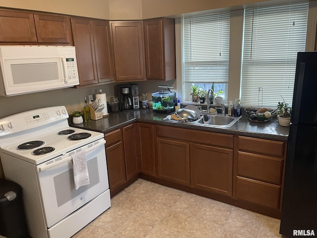 kitchen with a sink, dark countertops, white appliances, and brown cabinets
