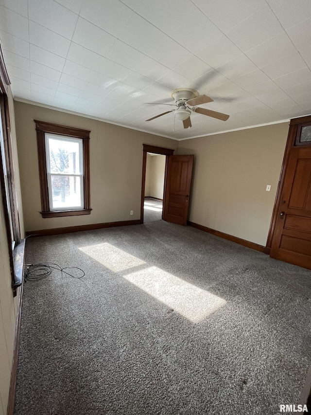 unfurnished bedroom featuring ceiling fan, carpet flooring, baseboards, and ornamental molding