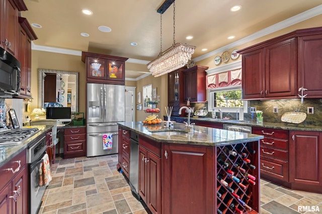 kitchen featuring pendant lighting, sink, a center island with sink, appliances with stainless steel finishes, and dark stone countertops