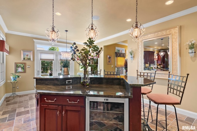 bar featuring dark stone countertops, ornamental molding, beverage cooler, and decorative light fixtures