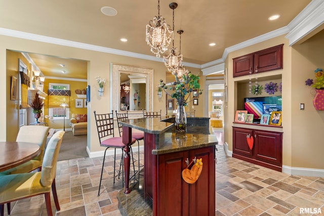 kitchen featuring dark stone countertops, hanging light fixtures, ornamental molding, and a chandelier