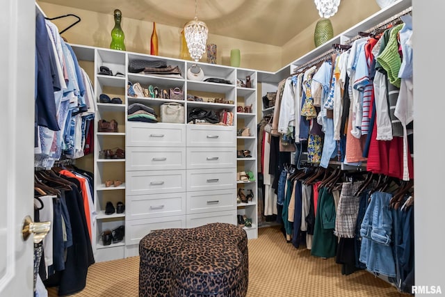 walk in closet with a chandelier and light colored carpet