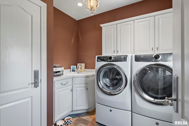 washroom with a chandelier, sink, washer and dryer, and cabinets