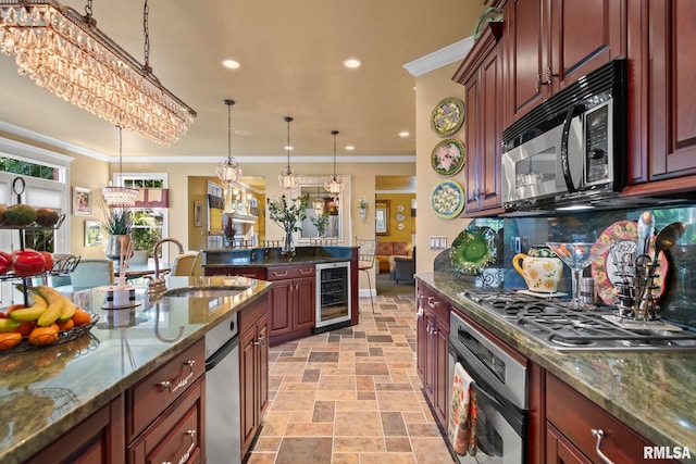 kitchen with appliances with stainless steel finishes, dark stone countertops, pendant lighting, crown molding, and beverage cooler