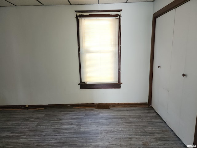 unfurnished bedroom featuring a paneled ceiling, dark hardwood / wood-style flooring, and a closet