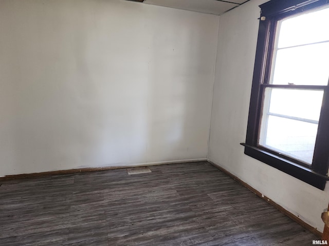 empty room featuring dark wood-type flooring and plenty of natural light