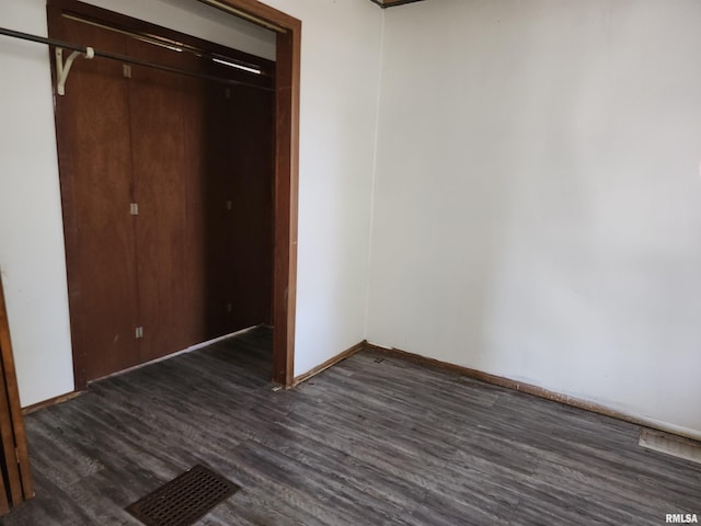 unfurnished bedroom with a closet and dark hardwood / wood-style flooring