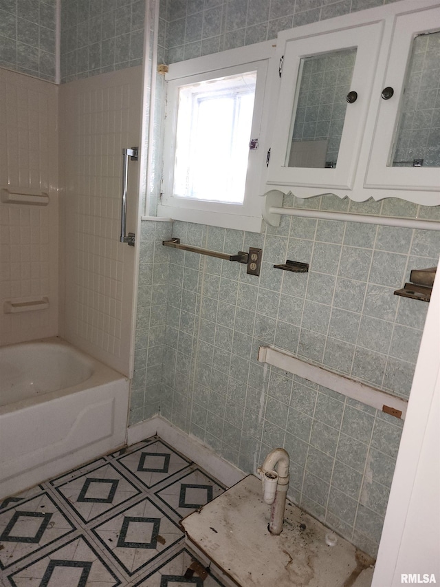 bathroom with tile walls and tiled shower / bath