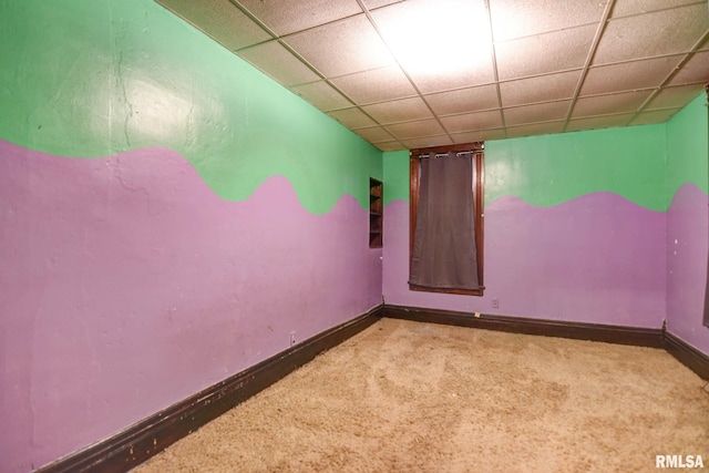 spare room featuring carpet floors, baseboards, and a drop ceiling