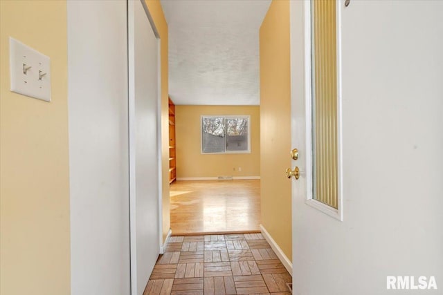 corridor featuring a textured ceiling and light parquet flooring