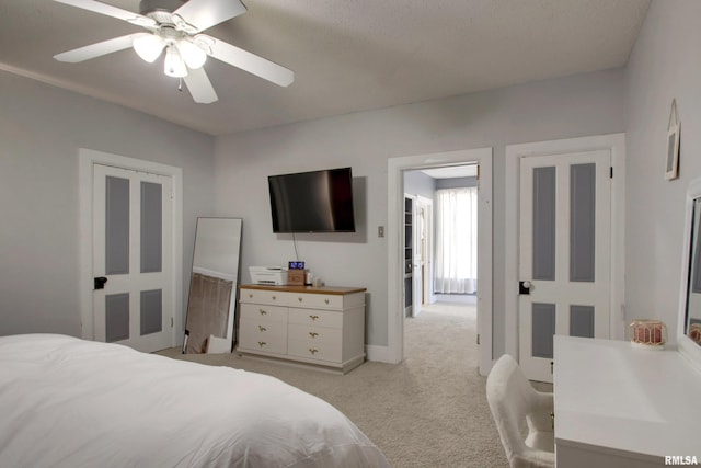 bedroom featuring ceiling fan, light colored carpet, and a textured ceiling