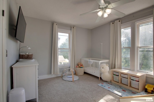 bedroom with ceiling fan, a nursery area, and carpet floors