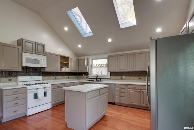 kitchen featuring sink, appliances with stainless steel finishes, a center island, light wood-type flooring, and decorative backsplash