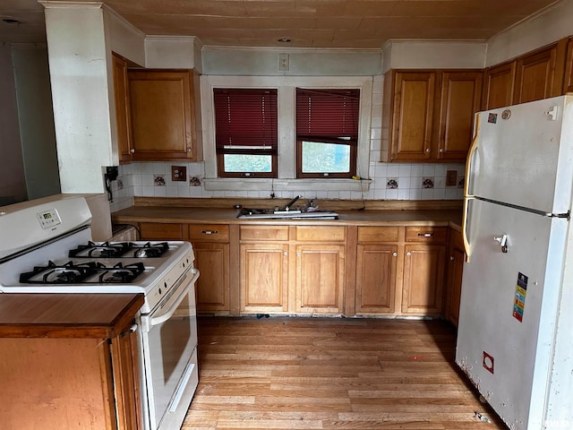 kitchen with sink, white appliances, tasteful backsplash, light wood-type flooring, and crown molding