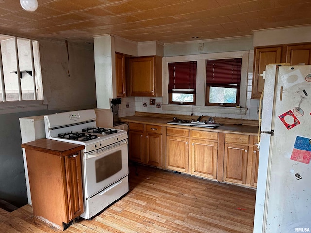 kitchen with a wealth of natural light, white appliances, light wood-type flooring, and sink