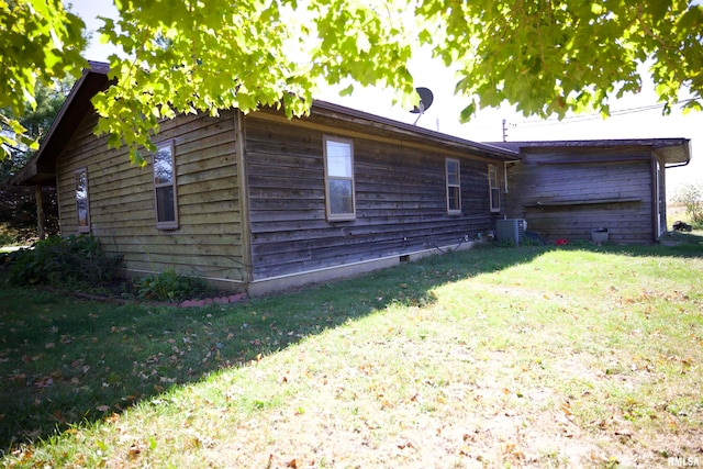 view of side of property featuring a lawn and central AC