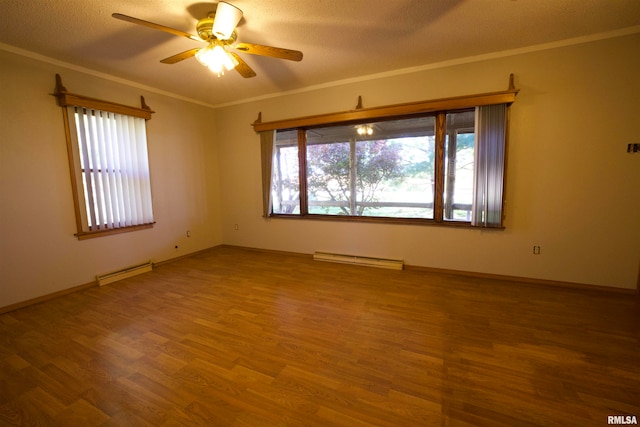 unfurnished room featuring a healthy amount of sunlight, baseboard heating, ceiling fan, and hardwood / wood-style flooring