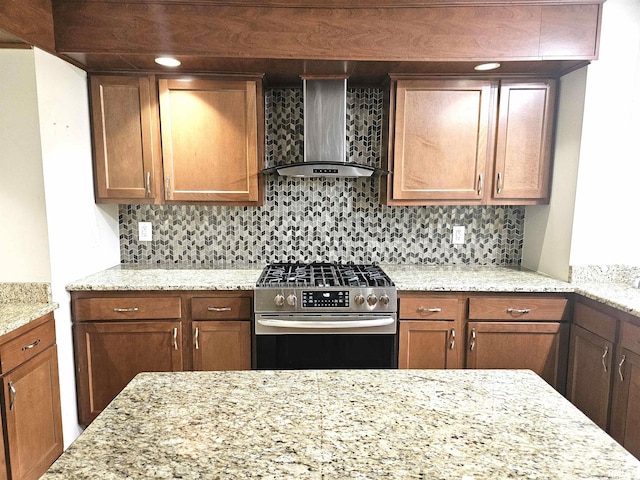 kitchen featuring light stone counters, wall chimney exhaust hood, backsplash, and high end range