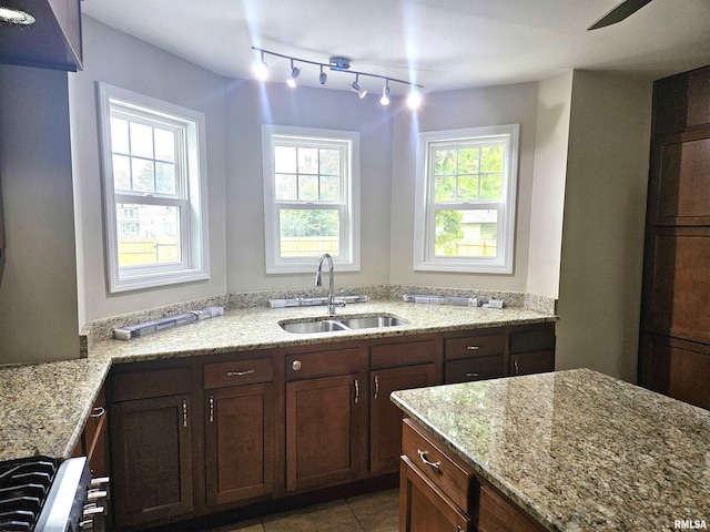 kitchen featuring light stone countertops, sink, range, and a wealth of natural light