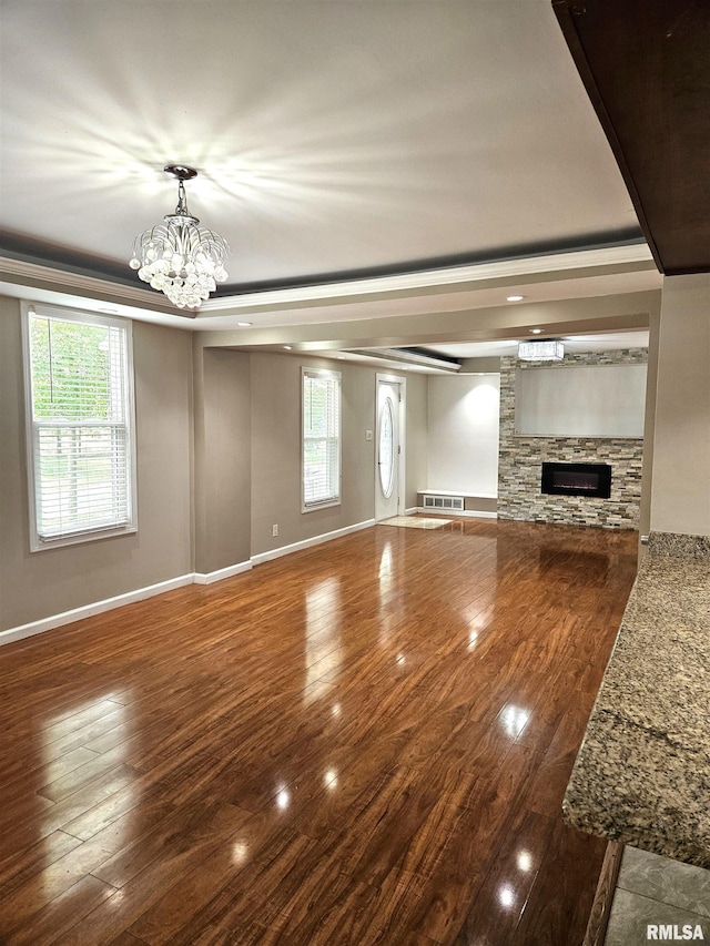 unfurnished living room featuring a healthy amount of sunlight, crown molding, and hardwood / wood-style flooring