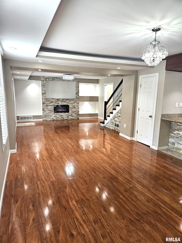 unfurnished living room with a fireplace, a chandelier, and hardwood / wood-style flooring