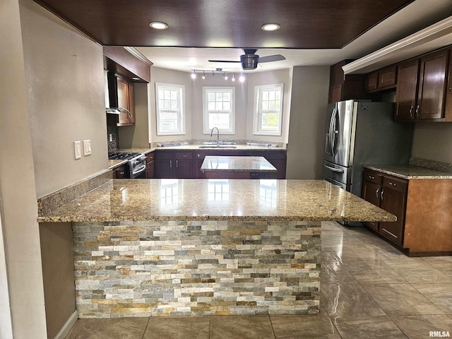 kitchen featuring sink, light stone countertops, kitchen peninsula, and stainless steel appliances