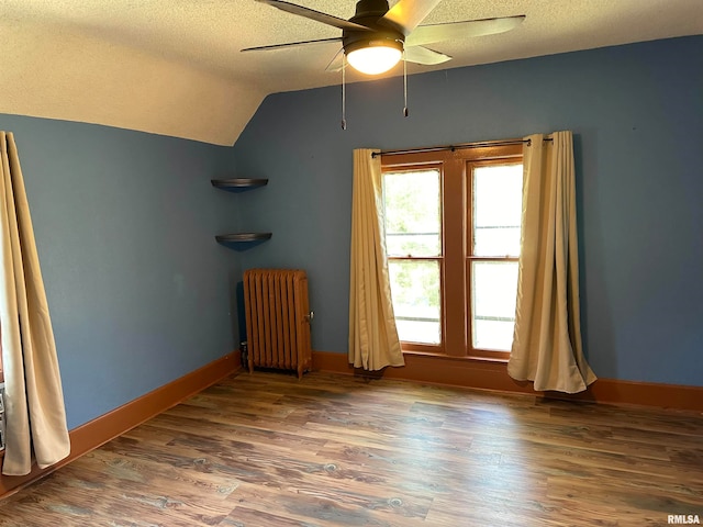 interior space featuring radiator heating unit, a textured ceiling, lofted ceiling, ceiling fan, and dark hardwood / wood-style floors