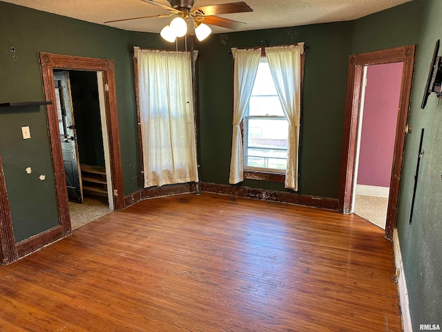 empty room with a textured ceiling, ceiling fan, and hardwood / wood-style flooring