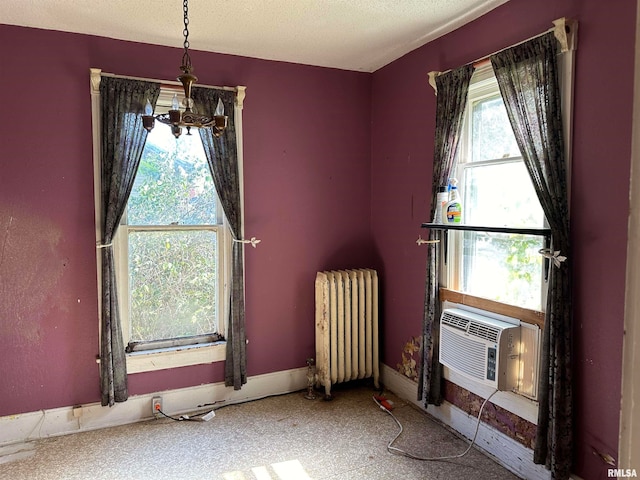 unfurnished room with an inviting chandelier, cooling unit, a textured ceiling, and radiator heating unit