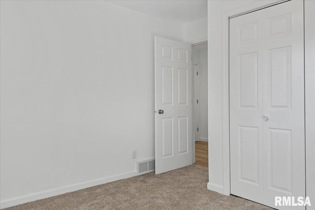 unfurnished bedroom featuring a closet and light colored carpet