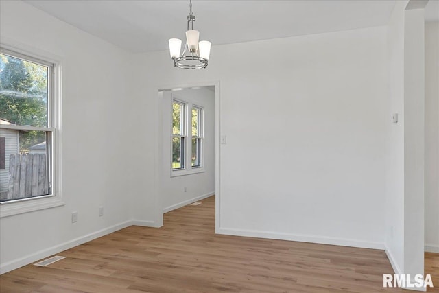 unfurnished dining area with a notable chandelier, plenty of natural light, and light hardwood / wood-style floors