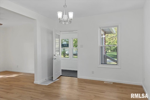 interior space with plenty of natural light, light hardwood / wood-style floors, and an inviting chandelier