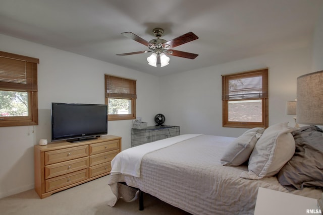 bedroom featuring ceiling fan, light colored carpet, and multiple windows