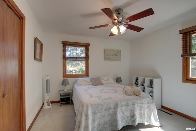 carpeted bedroom featuring a closet, multiple windows, and ceiling fan