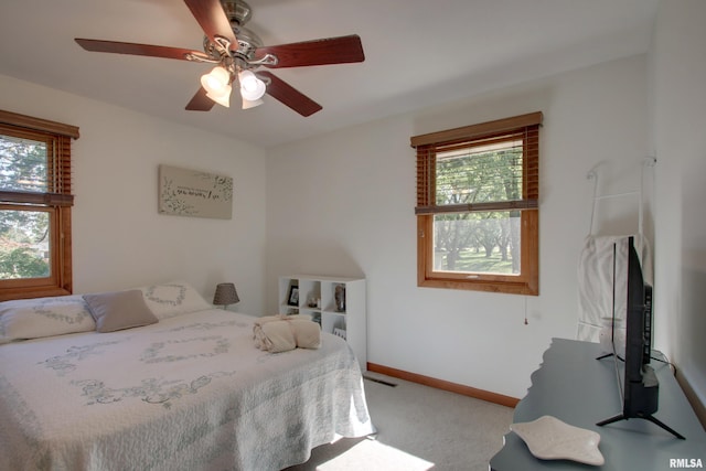 carpeted bedroom featuring multiple windows and ceiling fan