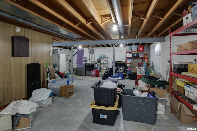 basement with white fridge and wooden walls