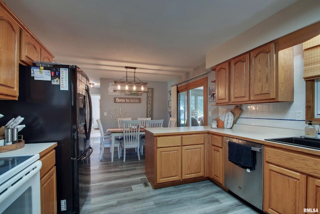 kitchen featuring dishwasher, light hardwood / wood-style floors, decorative light fixtures, and backsplash