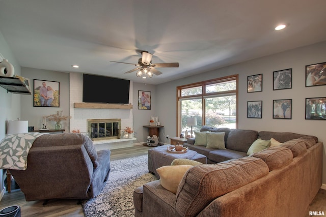 living room featuring a fireplace, wood-type flooring, and ceiling fan