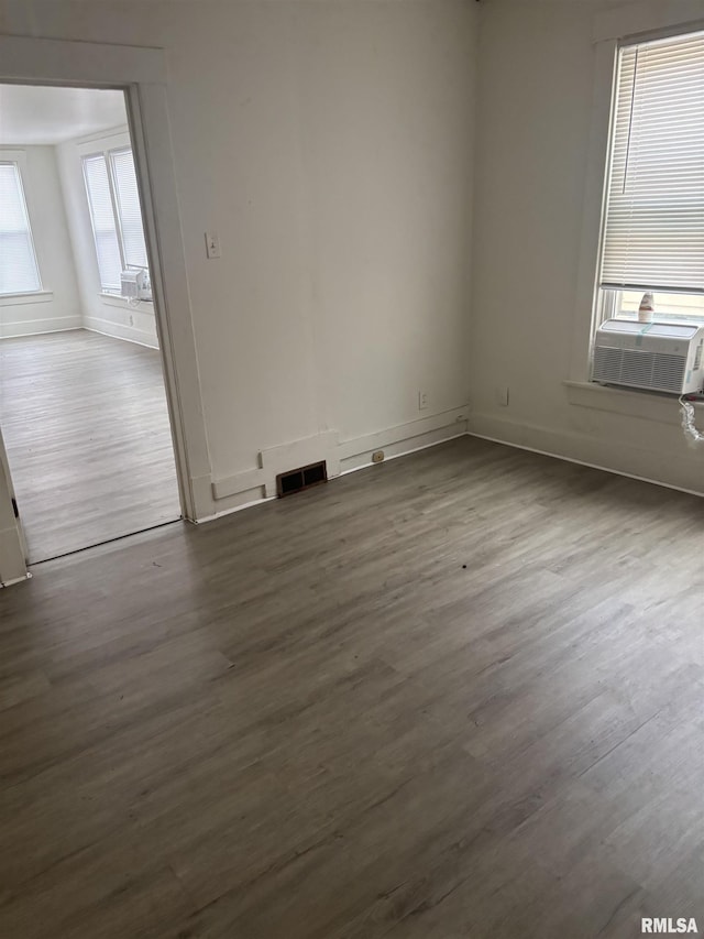 unfurnished room featuring cooling unit, plenty of natural light, and dark wood-type flooring