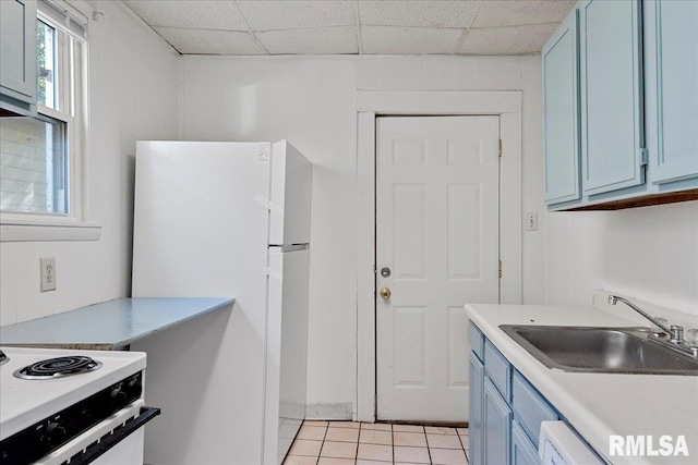 kitchen featuring blue cabinetry, light tile patterned floors, a drop ceiling, and sink