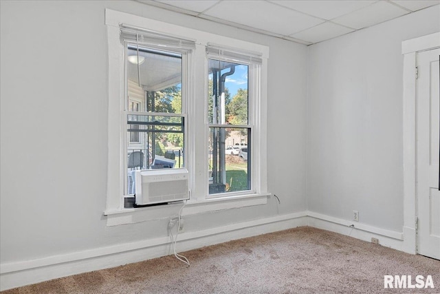 carpeted empty room featuring a drop ceiling