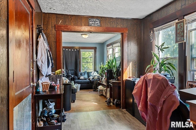 interior space with a textured ceiling, wooden walls, light hardwood / wood-style flooring, and a healthy amount of sunlight