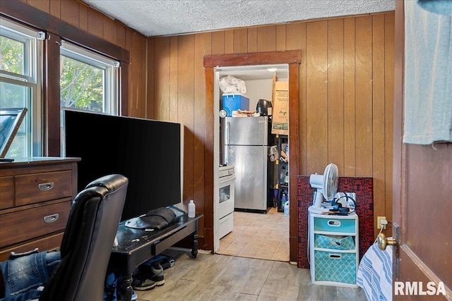 office space with wooden walls, a textured ceiling, and light wood-type flooring