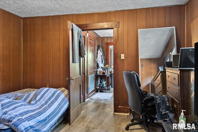 office with wood walls, light wood-type flooring, and a textured ceiling