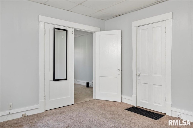 unfurnished bedroom with carpet flooring, a drop ceiling, and a closet