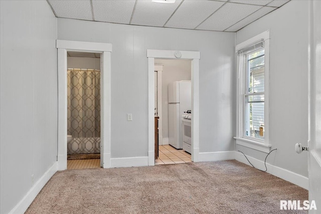 unfurnished bedroom featuring connected bathroom, a paneled ceiling, and light carpet