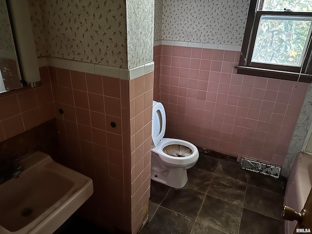 bathroom with sink, tile walls, and toilet