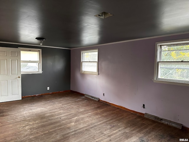 unfurnished room featuring crown molding, a baseboard heating unit, and dark hardwood / wood-style flooring