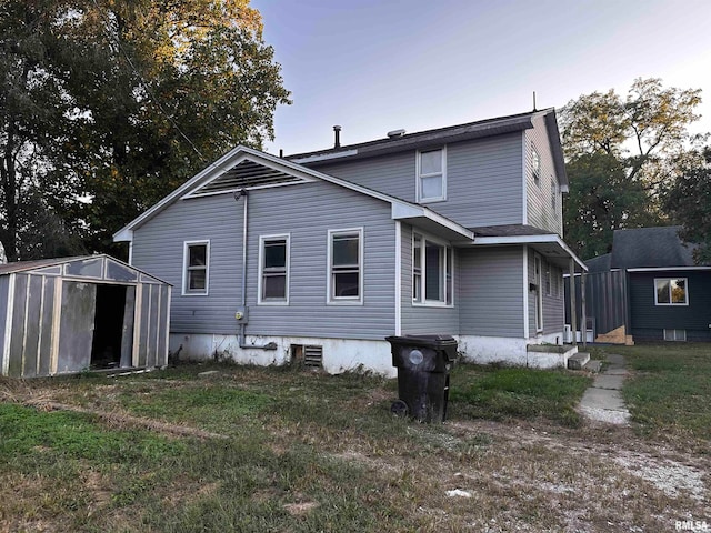 rear view of property with a storage shed and a lawn